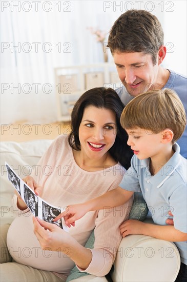 Father, mother and son (4-5) looking at ultrasound photo.