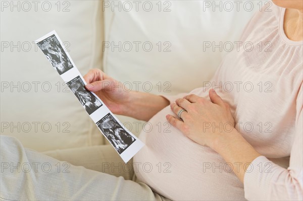 Pregnant woman looking at ultrasound photo.