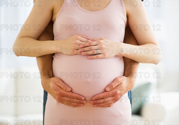 Midsection of man hugging pregnant woman.