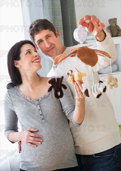 Expectant couple decorating baby room.