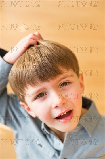 Portrait of boy (4-5) scratching head.