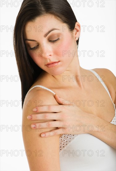 Studio shot of young woman caring for skin.