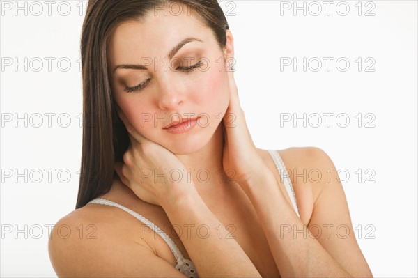 Studio shot of young woman caring for skin.