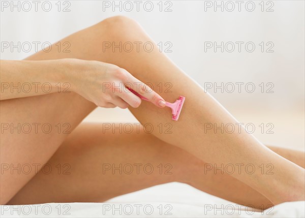 Studio shot of woman shaving legs.