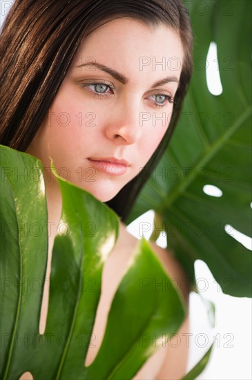 Studio shot of woman between leaves.