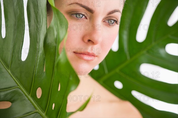 Studio shot of woman between leaves.