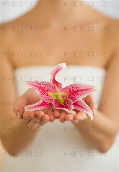 Studio shot of woman holding lily.