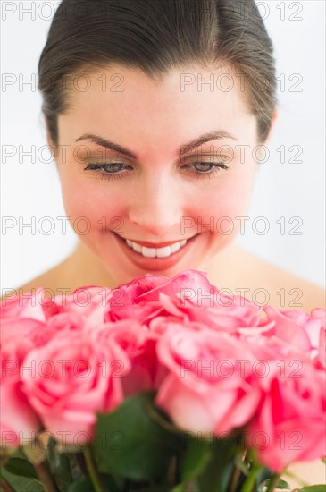 Studio shot of woman smelling roses.