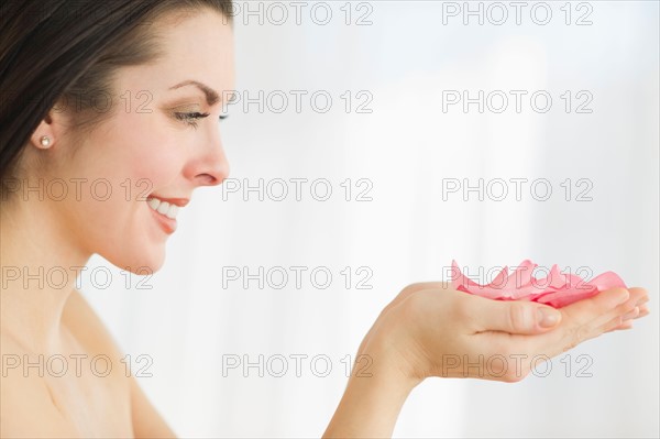 Studio shot of woman holding rose petals.