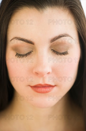 Studio portrait of young woman with eyes shut.