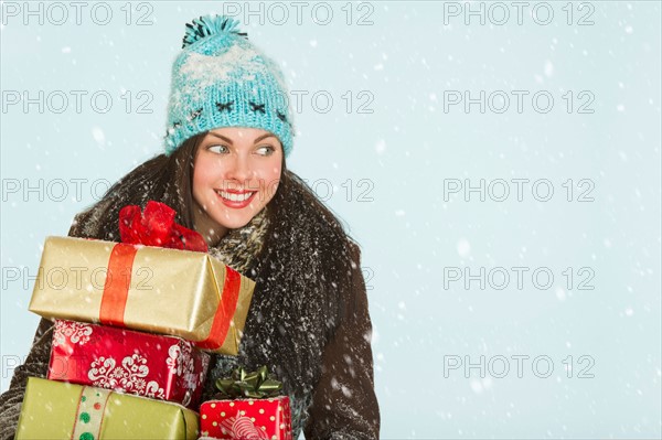 Studio portrait of woman in winter clothing carrying presents.