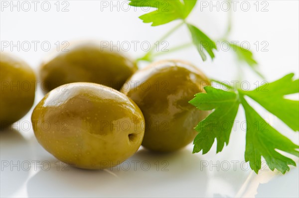 Close-up of green olives with fresh parsley, studio shot.