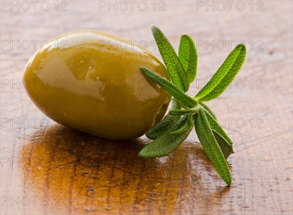 Close-up of green olive with rosemary, studio shot.