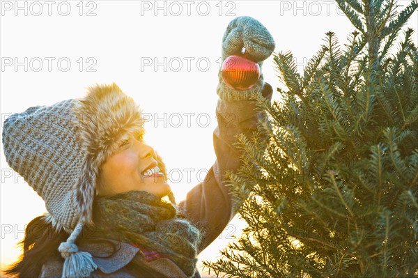 Smiling woman decorating Christmas tree.