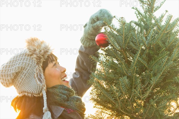 Smiling woman decorating Christmas tree.