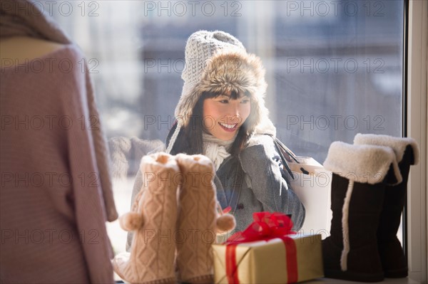 Smiling woman looking at shop display during Christmas shopping.