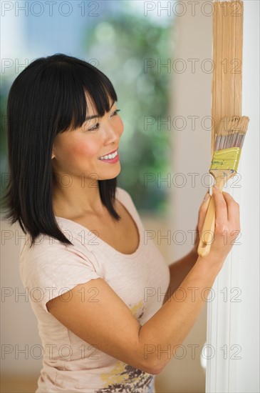 Smiling woman painting door frame.