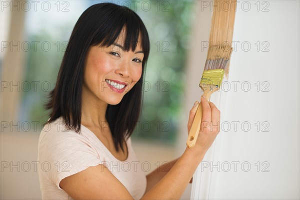 Smiling woman painting door frame.