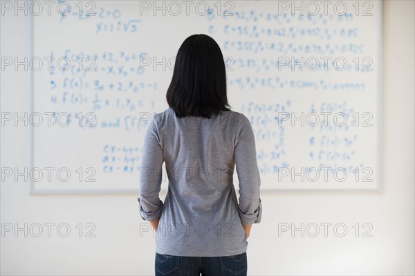 Woman standing in front of board with equations.