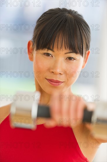 Mid adult woman exercising with dumbbells.