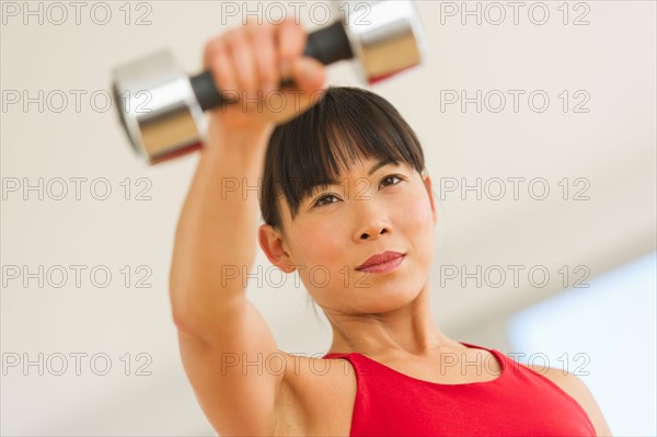 Mid adult woman exercising with dumbbells.