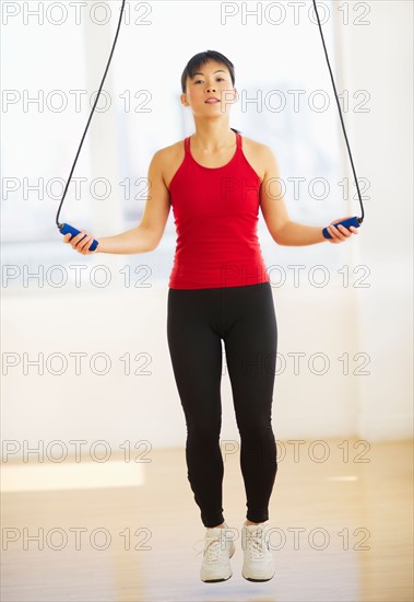 Mid adult woman training with skipping rope.