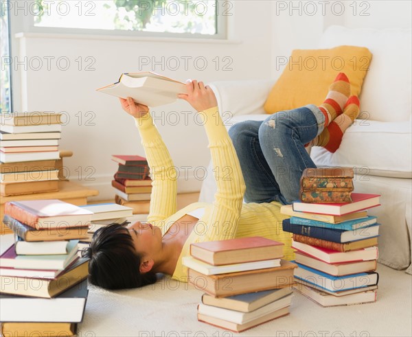 Woman reading among stacks of books.