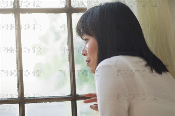 Thoughtful woman looking through window.