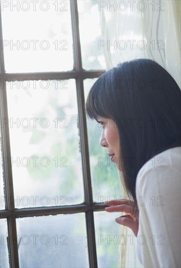 Thoughtful woman looking through window.