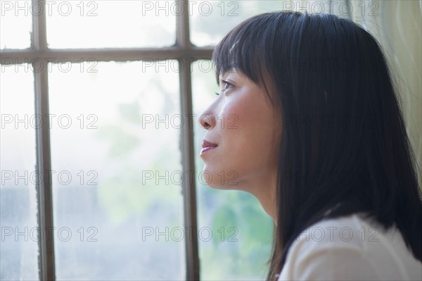 Thoughtful woman looking through window.