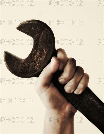 Hand holding wrench, studio shot.