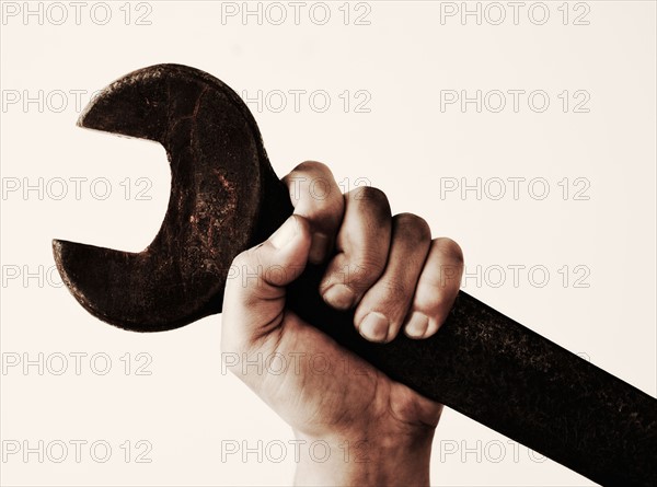 Hand holding wrench, studio shot.