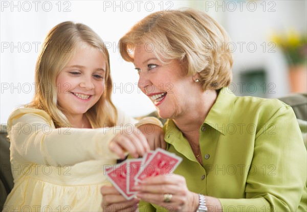 Grandmother with granddaughter (8-9) playing cards.