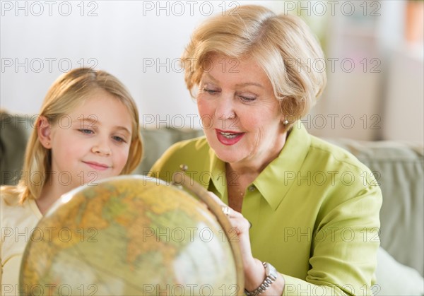 Grandmother with granddaughter (8-9) looking at globe.