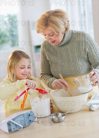 Grandmother with granddaughter (8-9) preparing food.