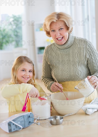 Grandmother with granddaughter (8-9) preparing food.