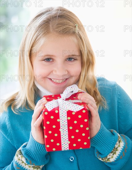 Portrait of smiling girl (8-9) holding gift.