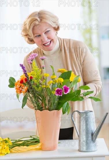 Smiling senior woman arranging flowers.