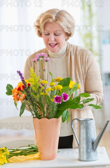 Smiling senior woman arranging flowers.