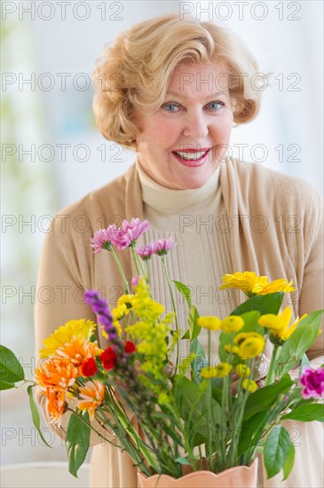 Smiling senior woman arranging flowers.