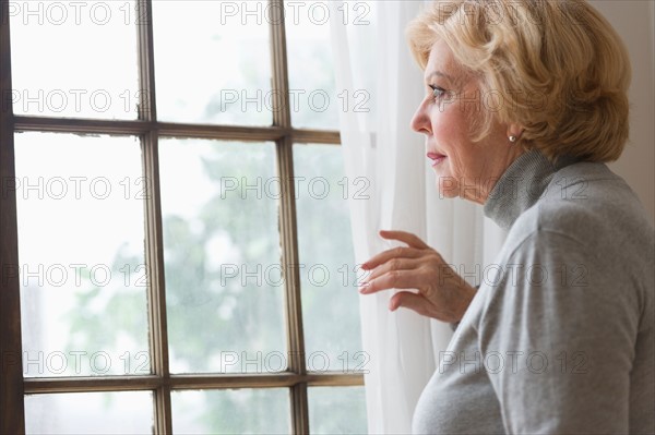 Portrait of senior woman looking through window.