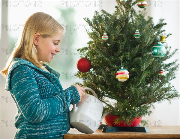 Girl watering christmas tree.