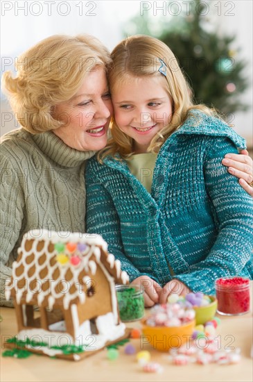 Grandmother with granddaughter (8--9) making gingerbread house.