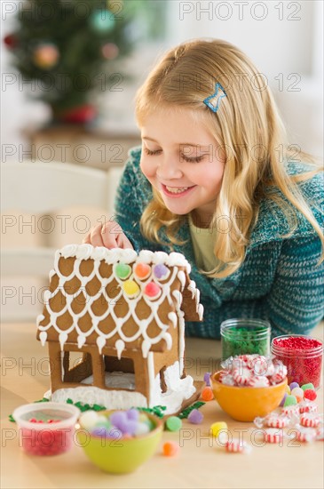 Girl (8--9) making gingerbread house.