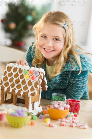 Girl (8--9) making gingerbread house.
