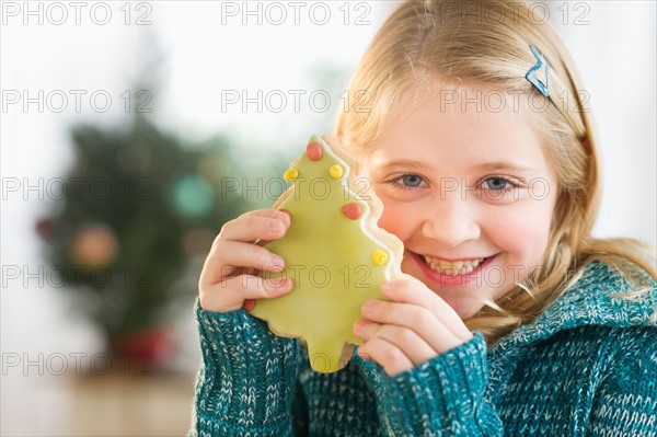 Girl (8--9) holding gingerbread cookie.