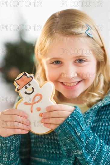 Girl (8--9) holding gingerbread cookie.