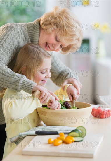 Grandmother and granddaughter (8-9) preparing salad together.