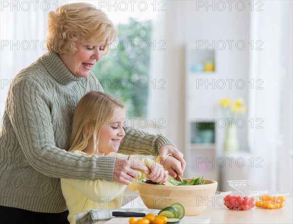 Grandmother and granddaughter (8-9) preparing salad together.