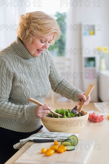 Senior woman preparing salad .